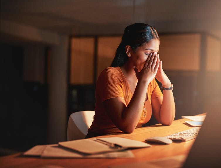 Young businesswoman feeling stressed and sitting alone in her office at night